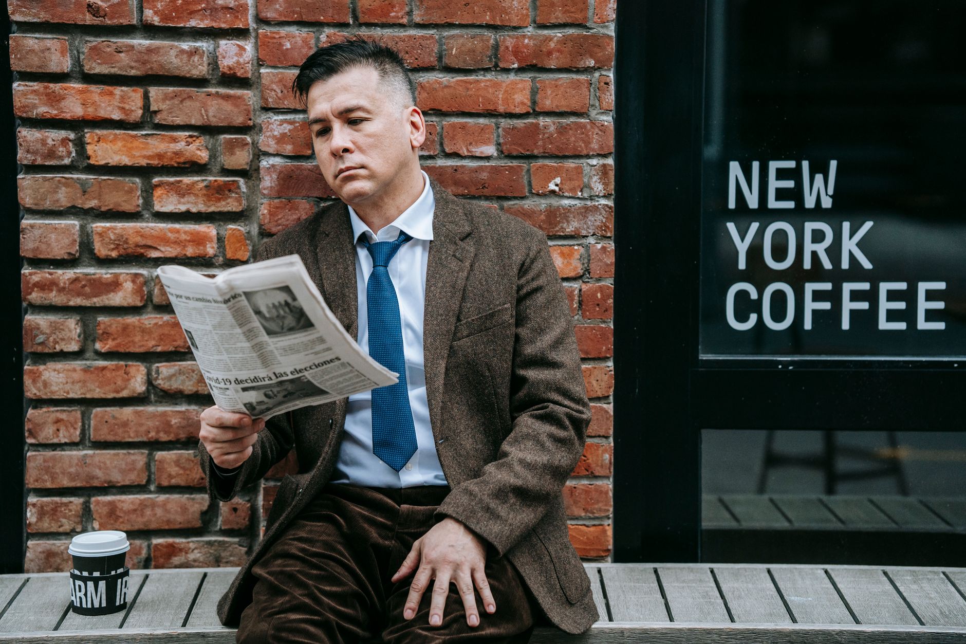 A professional man in formal wear reads a newspaper beside a coffee shop window. — Die Signaturspiele, die du bei Tron Casino