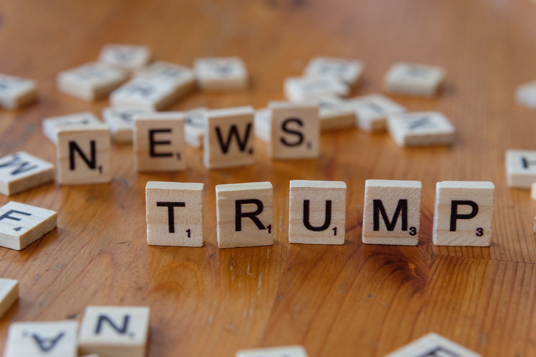 Wooden letter tiles spell 'NEWS' and 'TRUMP' on a wooden table, relating to political discourse. — Instant Casino Erlebnisse: