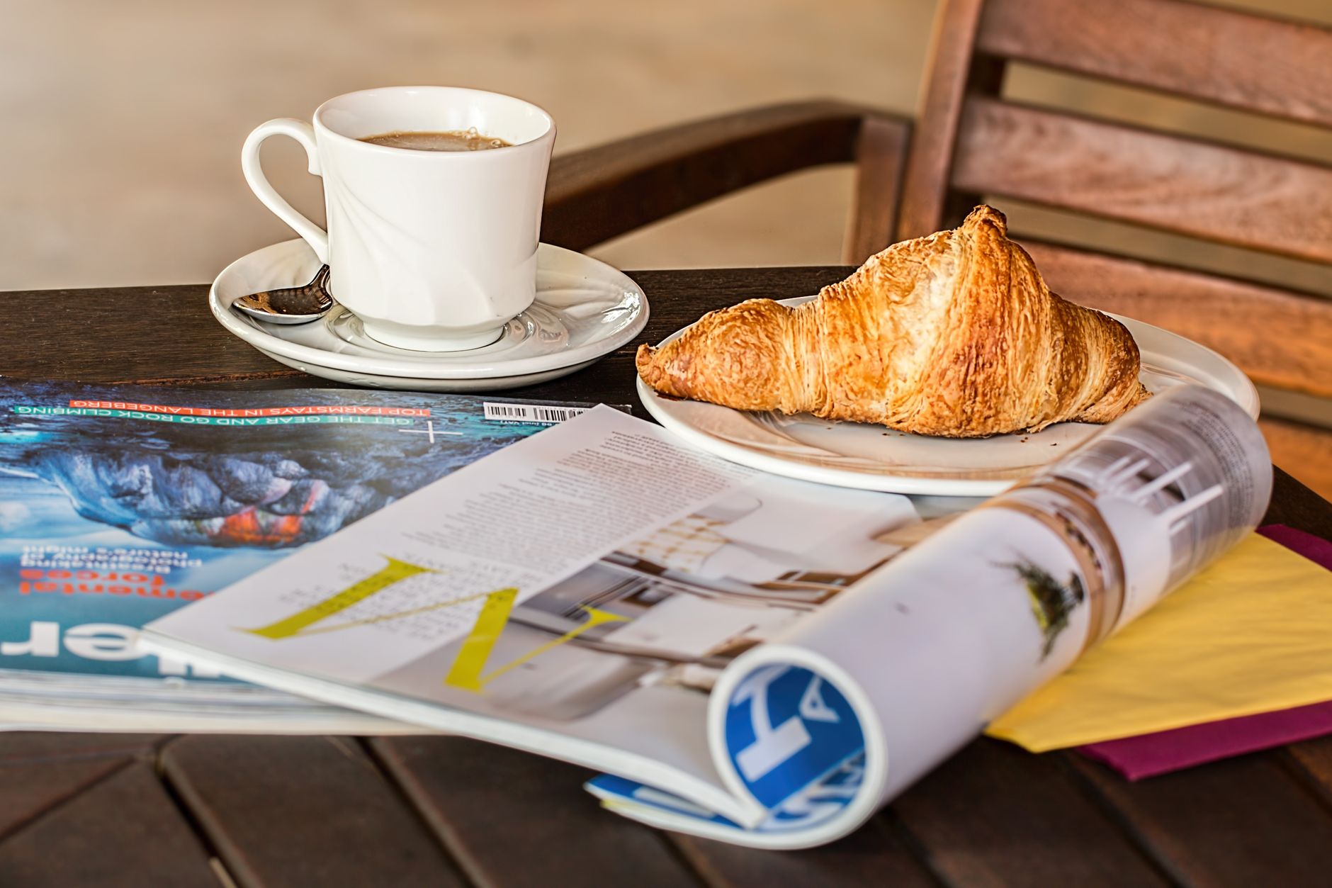 Enjoy a peaceful morning with coffee, croissant, and reading material on a wooden table. — Kundenservice im Casoo Casino: Wie