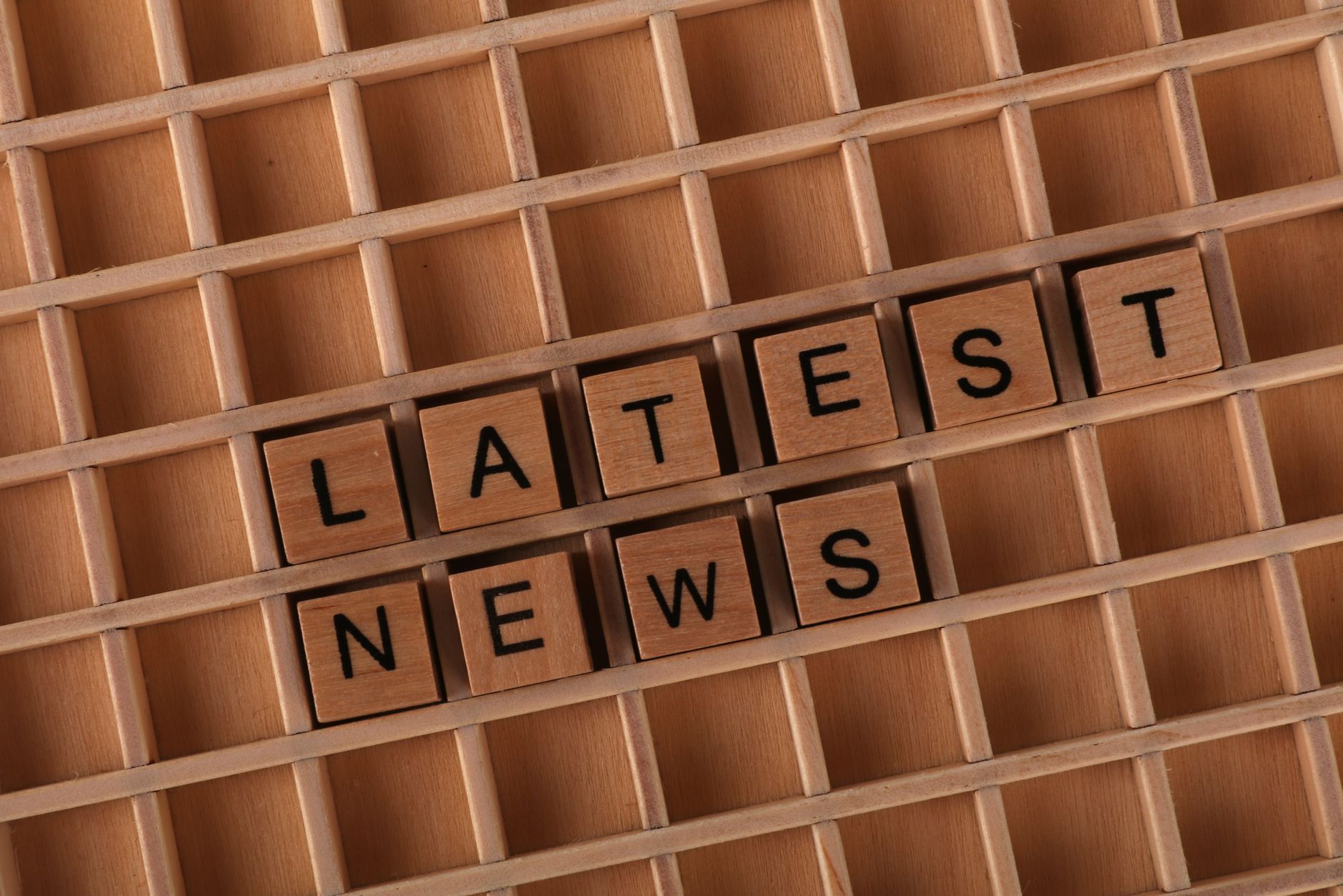 Wooden letter blocks spelling 'Latest News' on a grid surface. Ideal for media concepts. — LiraSpin: Twoja szybka przygoda ze
