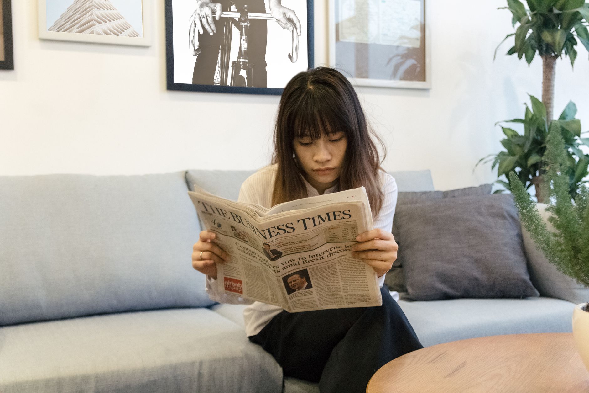A young woman attentively reads a newspaper while sitting on a modern sofa indoors. — Sicherheitssiegel beim Mega Medusa Casi