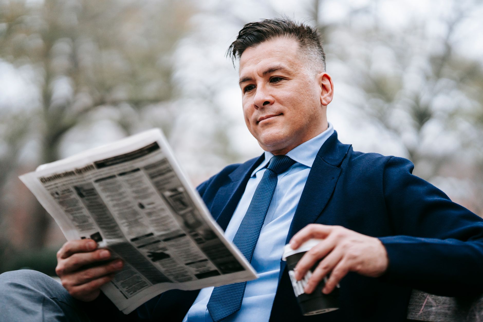 Stylish man in formal wear enjoys a drink while reading a newspaper outside. — Was bietet die mobile App von Fambet Casino?